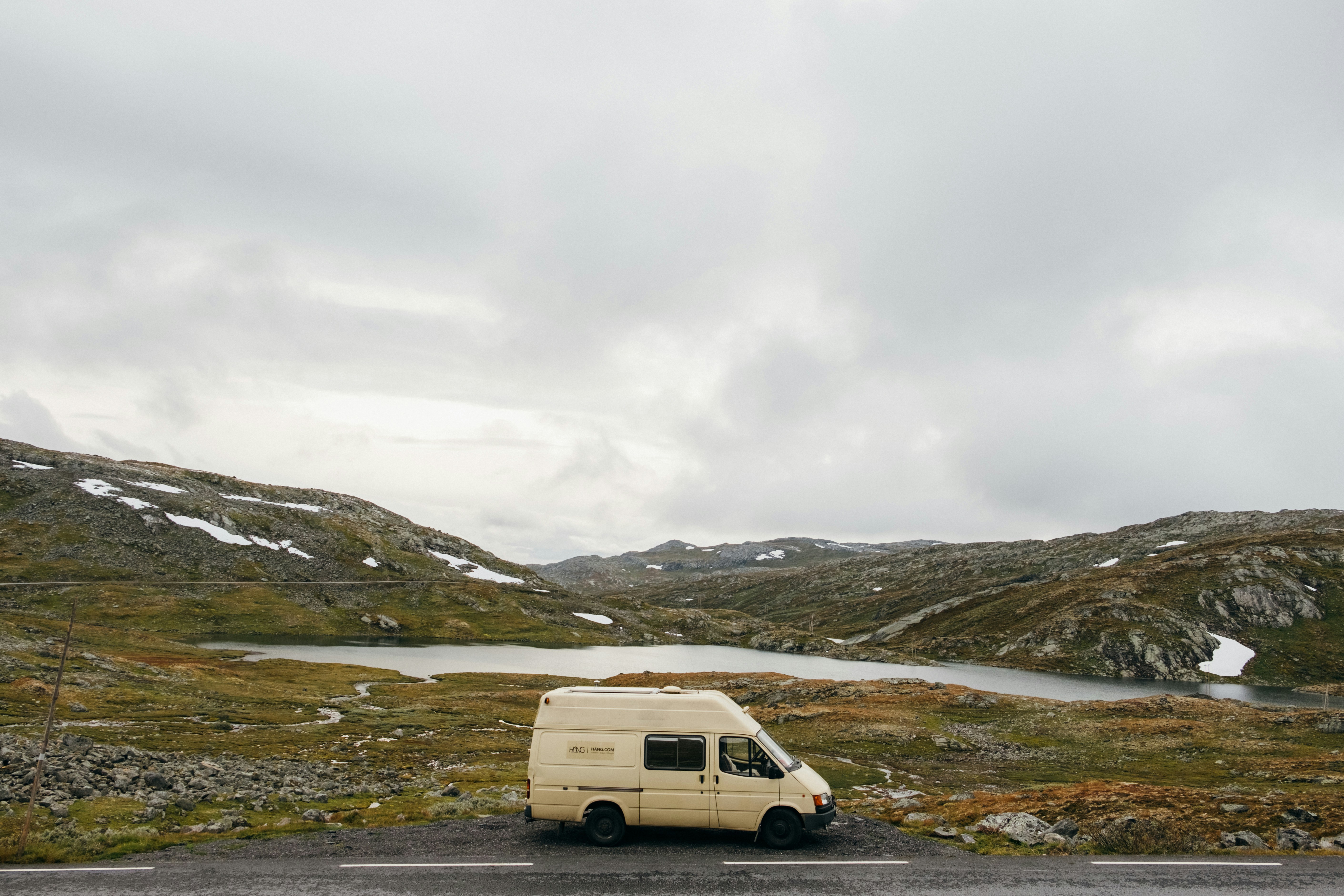 White van on a green grass field under a cloudy sky in New Zealand